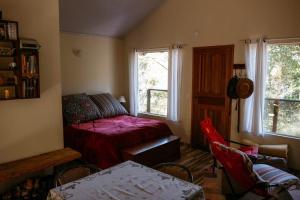 a bedroom with a red bed and a table and chairs at Chalé da Mata in Sapucaí-Mirim