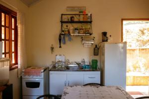 a small kitchen with a sink and a refrigerator at Chalé da Mata in Sapucaí-Mirim