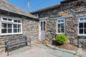 a stone house with a bench in front of it at Cottage 3 Old Farmhouse Mews in Keswick