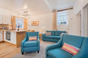 a living room with two blue chairs and a kitchen at Cottage 3 Old Farmhouse Mews in Keswick