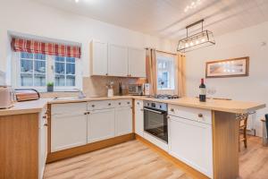 une cuisine avec des armoires blanches et un comptoir dans l'établissement Cottage 3 Old Farmhouse Mews, à Keswick