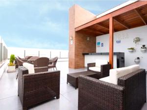 a patio with wicker chairs and tables on a balcony at Beautiful apartment Near airport /cozy Oceanfront in Lima