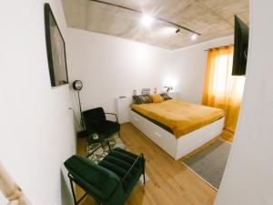 a bedroom with a bed and a chair in it at meebo apartments in Novi Sad
