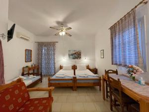 a room with two beds and a table and chairs at Villa Gelly's Studios in Aliki