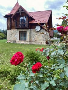 a house with red roses in front of a building at Sofiya in Mykulychyn