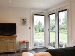 a living room with a tv and two sliding glass doors at The Harwell in Assington