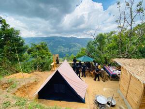 a group of people standing around a tent in the dirt at The Cliff Tea Glamping in Badulla