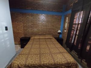 uma cama num quarto com uma parede de tijolos em Dpto Alma en Calma San Rafael em São Rafael