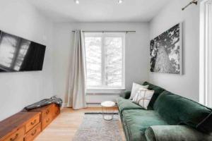 sala de estar con sofá verde y ventana en Luxury Retreat en Mont-Tremblant