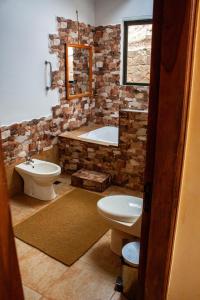 a bathroom with a tub and a toilet and a sink at Cabaña Los Guapurús in Samaipata