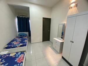 a bedroom with two beds and a tv in it at De’ Nuhir Homestay Teluk Senangin 