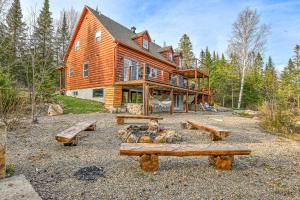 a large wooden house with logs in front of it at River Rock Retreat in Notre-Dame-de-la-Merci