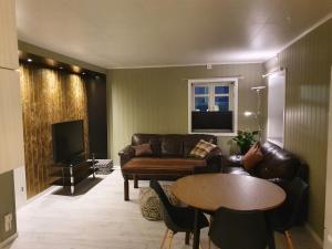 a living room with a couch and a table at Åsveien Apartments. in Harstad