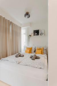 a white bedroom with a large bed with yellow pillows at Stilvolle, gemütliche Wohnung mitten im ZENTRUM in Leipzig