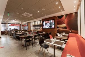 a restaurant with tables and chairs and a flat screen tv at ibis Lima Reducto Miraflores in Lima