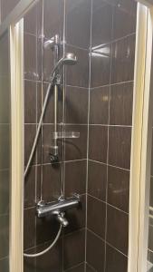 a shower in a bathroom with a brown tiled wall at Absolute Center Helsinki Compact Apartment in Helsinki