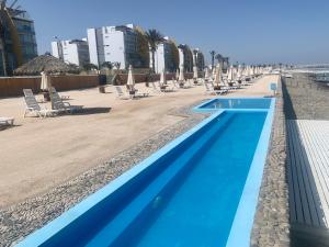 una piscina con sillas y sombrillas en una playa en 501 Velas Primera Fila Vista Bahía Paracas 110 Metros - 501 T1, en Paracas