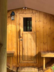 un edificio de madera con una puerta y un banco en de Harmonie, en Molenhoek