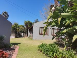 uma casa branca com um quintal com relva verde em A&F Cottage with pool n braai em Sandton