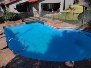 a large blue swimming pool in front of a house at A&F Cottage with pool n braai in Sandton