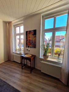 um quarto com duas janelas e uma mesa com um candeeiro em City-Wohnung Salzwedel em Salzwedel