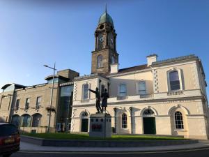 a building with a statue in front of it with a clock tower at Central Lisburn Duplex Apartment No Parties in Lisburn