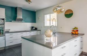 a kitchen with white cabinets and blue walls at Maison familiale au calme avec piscine securisee in Le Barp +8 photos