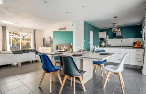 a kitchen with blue and white chairs and a table at Maison familiale au calme avec piscine securisee in Le Barp