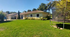a yard with a house and a swing at Maison familiale au calme avec piscine securisee in Le Barp