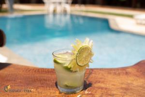 a drink sitting on a table next to a swimming pool at Pousada Yapara-Tyba in Japaratinga