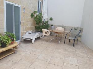 300 years old apartment with a lot of character في Qormi: فناء فيه كراسي وطاولة وكراسي