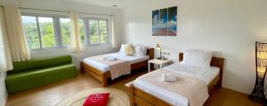 een kamer met 2 bedden en een groene bank bij La View Mountain Resort in Damasanan