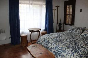 a bedroom with a bed and a window with blue curtains at Loma de las Maravillas in Curacaví