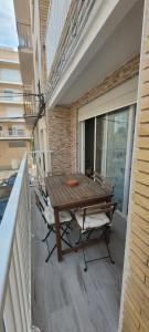 patio z drewnianym stołem i krzesłami na balkonie w obiekcie Precioso piso, todo equipado a 300m de las playas w mieście L'Ametlla de Mar