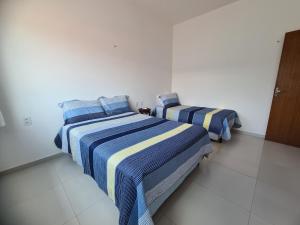 two beds in a white room with blue and yellow stripes at Casa 22 Lençóis Maranhenses - Barreirinhas - MA in Barreirinhas