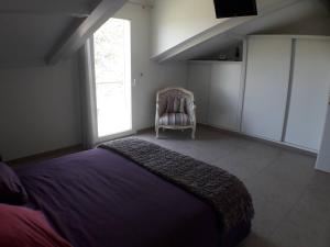 a bedroom with a bed and a chair and a window at 170 m² entre Lyon et St Etienne in Saint-Martin-la-Plaine