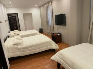 Habitación de hotel con 3 camas y TV de pantalla plana. en Alston Inn Hotel en Quito