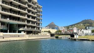 a large apartment building next to a river with a bridge at Canal Quays 507 in Cape Town