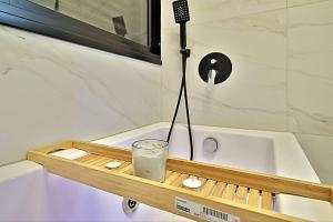 a wooden tray with a drink on a bath tub at T'eo 25 suite in Qiryat Yam