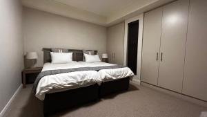 een slaapkamer met een groot bed met witte lakens en kussens bij Canal Quays 507 in Kaapstad