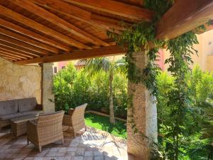 a patio with wicker chairs and a wooden pergola at Giolet's House in Villasimius