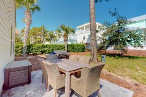 a patio with a wooden table and chairs and palm trees at 51 Magical Place in Santa Rosa Beach