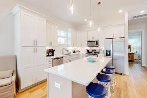 a kitchen with white cabinets and a large island with blue stools at 51 Magical Place in Santa Rosa Beach