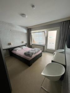 ミッデルケルケにあるSorghvlietのベッドルーム1室(ベッド1台、窓、椅子付)