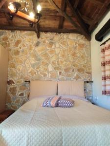 a bed in a room with a stone wall at ΦΙΛΥΡΑ ΠΕΤΡΙΝΟ in Kernitsa