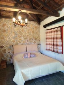 a bedroom with a bed in a stone wall at ΦΙΛΥΡΑ ΠΕΤΡΙΝΟ in Kernitsa