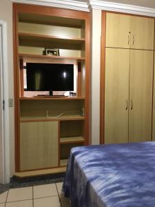 um quarto com uma cama, uma televisão e armários em Rio Quente - DiRoma em Rio Quente