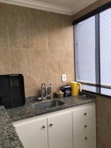 um balcão de cozinha com um lavatório e uma janela em Rio Quente - DiRoma em Rio Quente