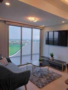 een woonkamer met een bank en een groot raam bij 1BEDROOM Unit at Azure north With Netflix up to 6PAX in San Fernando