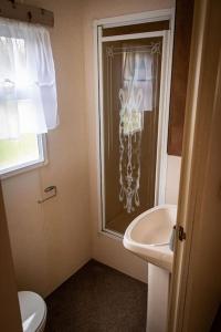 a bathroom with a sink and a toilet and a window at 57 Peaceful Corner Caravan in Balminnoch